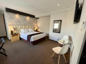 利马Hotel Ferre Miraflores的酒店客房带一张床、一张桌子和椅子