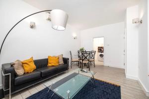 泰晤士河畔金斯顿2BR 2Baths ground floor garden apartment的客厅配有黑色沙发和桌子