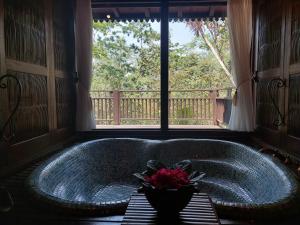 婆罗浮屠美萨提拉Spa度假村的窗户前的浴缸,有一碗鲜花