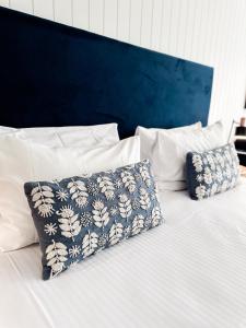 拜伦湾拜伦湾波浪酒店的一张带两个枕头的白色床和蓝色床头板