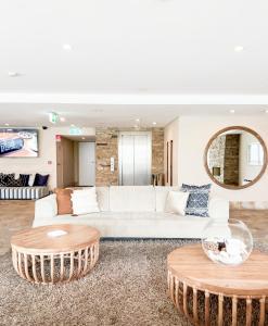 拜伦湾拜伦湾波浪酒店的客厅配有白色沙发和2张桌子