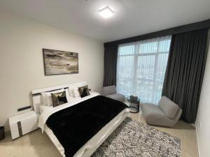 阿吉曼CMA Skyline Sanctuary Apartments - Ajman Corniche UAE的卧室配有床、椅子和窗户。