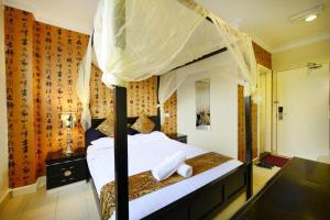 莎阿南Seeds Hotel Shah Alam Section 7的卧室配有带白色床单的天蓬床