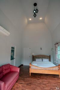 Tha KradanSuriyan Villa Erawan Kanchanaburi สุริยัน วิลล่า เอราวัณ กาญจนบุรี的一间卧室配有一张床和一张红色的沙发