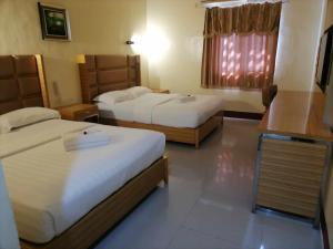MidsayapAsia Novo Boutique Hotel - Midsayap的酒店客房设有两张床和窗户。