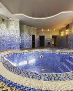 奇姆肯特Saule Guest House的大楼内一个蓝色瓷砖的大型游泳池