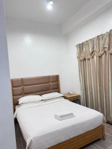 公主港吉姆克皇家酒店-巴拉望的卧室配有一张带白色床单的大床和窗户。