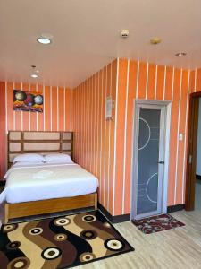 公主港吉姆克皇家酒店-巴拉望的一间卧室配有一张床和橙色条纹墙壁