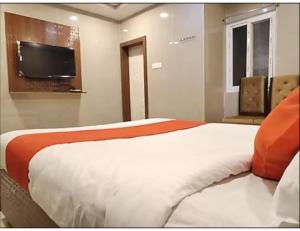 瓦朗加尔Hotel Grand Inn, Warangal的一间卧室配有一张床和一台平面电视