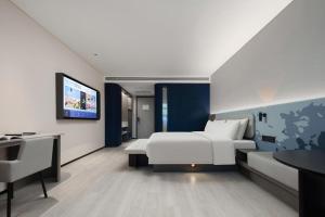 德清湖州德清莫干山轻居酒店的一间酒店客房,配有一张床和一台电视