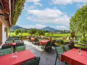 蒂罗尔州基希多夫纽沃特酒店的庭院配有红色桌椅,背景为山脉