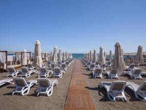 安塔利亚Elysium Deluxe Suites Antalya的海滩上的一排躺椅和遮阳伞