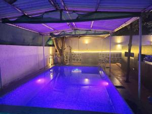 卡尔贾特BnBBuddy- Great Escape@Karjat, Maharashtra的一座建筑中一座带紫色灯光的室内游泳池