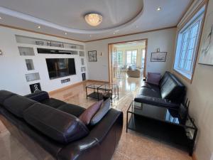 阿克雷里Villa Mafini的客厅配有黑色皮革家具和电视