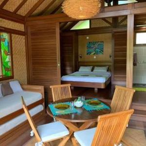 FarinoOasis de Tendéa - Bali à Farino的配有一张床和一张桌子及椅子的房间