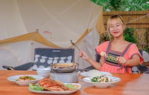 塞友BaanRai KhunYa บ้านไร่คุณย่า的站在餐桌上拿着食物盘的女人