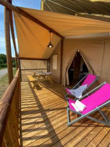 拉波勒Village Camping La Roseraie的帐篷配有带椅子和桌子的甲板