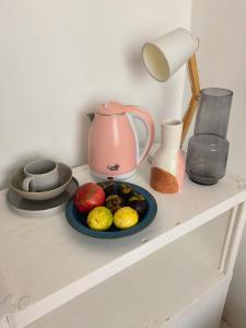 科伦坡Cozy Apartment的一张桌子,上面放着一盘水果和一盆粉红色茶壶