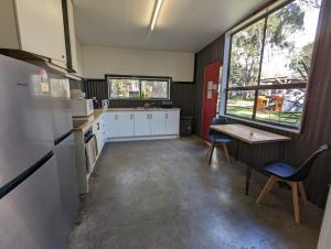 Dadswells BridgeTiny House 14B at Grampians Edge的厨房配有白色橱柜和桌椅