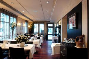 乌斯特Hotel Ochsen的餐厅设有白色的桌椅和窗户。