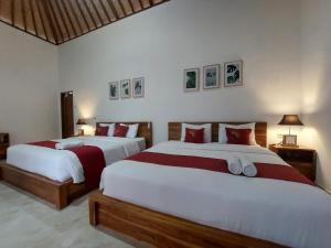 珀尼达岛Innora Jungle Resort And Spa的卧室内的两张床,配有红色和白色床单