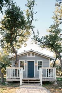 约翰逊城McKamy Cottage at Wrenwood Ranch, King Bed的白色的房子,有蓝色的门和两棵树