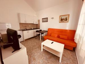 蒂亚斯Bungalows Doble UVE的一间带橙色沙发的客厅和一间厨房
