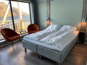HamnaVærlandet Havhotell的一张位于带两把椅子和大窗户的房间的床铺
