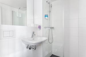苏黎世玛塔酒店的白色的浴室设有水槽和淋浴。