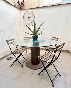 穆尔西亚Apartamento San Juan 1的一张带两把椅子的玻璃桌和一株立在立柱上的植物