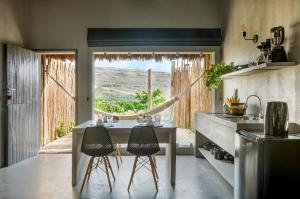 普拉亚德莫伊塔斯Vila Flor Studios的厨房配有桌子和两把椅子,设有窗户。