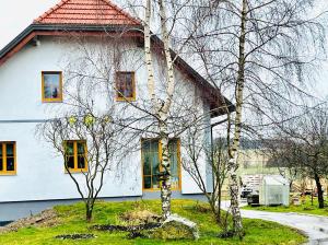 OttenschlagPrivatzimmer Fam. Führer的白色的房子,有黄色的窗户和树木