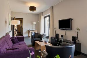 UithuizermeedenHunzego Hotel的客厅配有紫色沙发和电视