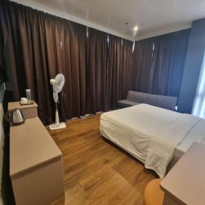碧瑶Eekos Hotels的一间卧室配有一张床和一张带风扇的书桌