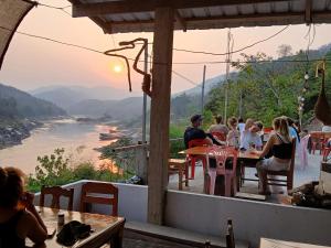 北宾Villa Mekong Guesthouse的一群人坐在桌子上,俯瞰河流