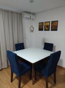 新彼得罗波利斯Apartamento Cantinho do Aconchego-Nova Petrópolis的客房内的白色桌子和蓝色椅子