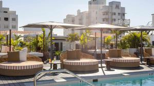 迈阿密海滩Uma House by Yurbban South Beach的一个带桌子和遮阳伞的庭院和一个游泳池