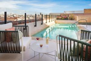 马德里阿托查加泰罗尼亚酒店的阳台设有游泳池和带酒杯的桌子。