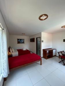 嘎林海斯港Pousada Recanto Pontal de Maracaipe的一间卧室配有红色的床和一张桌子