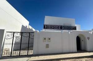 迈来亚Dar El Kahina Djerba的白色的建筑,设有大门和阳台