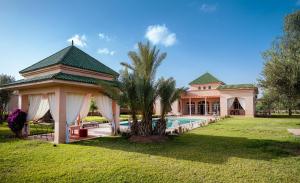 马拉喀什Palais Alcazar的一座带游泳池和棕榈树的房子