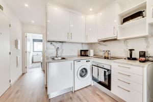 里斯本Lapa Stylish Apartments的厨房配有白色橱柜、洗衣机和烘干机