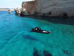 帕罗斯岛CycladesCharters: Discover Hidden Gems in Paros!的悬崖边的水中小船