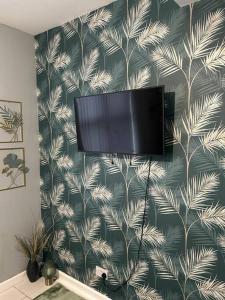 谢菲尔德Cozy Downtown Studio Flat in Sheffield的挂在墙上的平面电视,带有热带壁纸