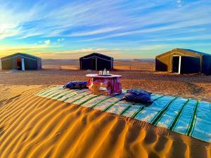 姆哈米德Mhamid Sahara Camp - Mhamid El Ghizlane的沙漠中一张桌子,上面有帐篷