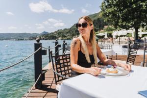 萨罗Hotel Spiaggia d'Oro - Charme & Boutique - Garda Lake Collection的坐在餐桌上吃一盘食物的女人