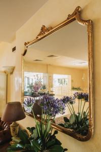 萨罗Hotel Spiaggia d'Oro - Charme & Boutique - Garda Lake Collection的墙上的镜子,桌子上布满紫色花
