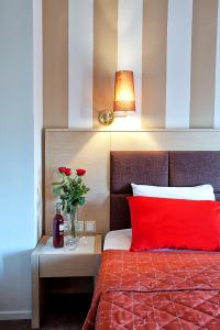 卡斯托里亚安纳斯塔希亚酒店的一张带红色枕头的床和红色玫瑰花瓶