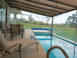 拉塔昆加BellaVista Casa de Montaña的庭院设有游泳池、椅子和桌子。