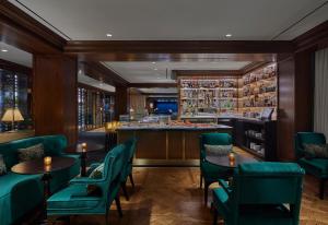 华盛顿华盛顿瑰丽酒店的一间设有绿色椅子的餐厅和一间酒吧